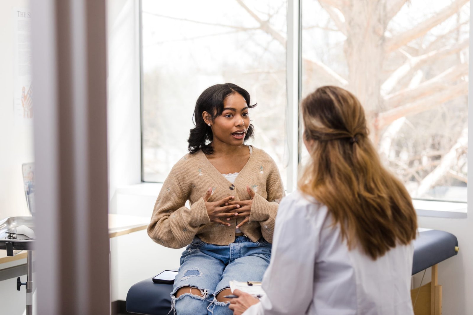 A young woman describing her symptoms to a clinician during a consultation
